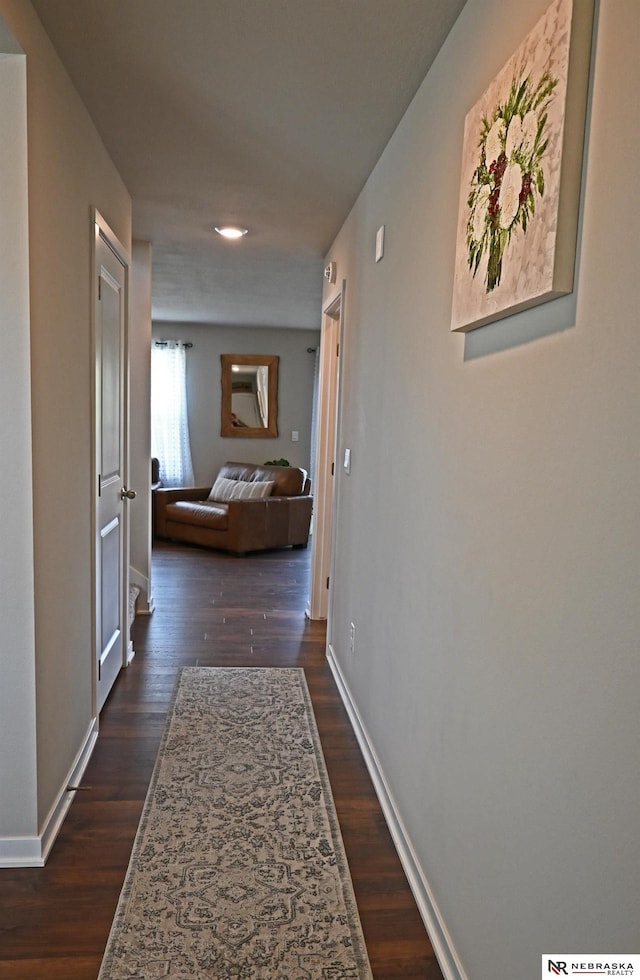 corridor with dark wood-type flooring, baseboards, and recessed lighting