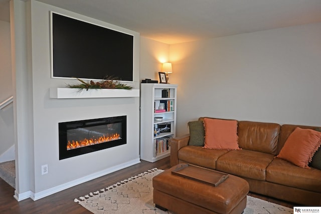 living room with baseboards, a glass covered fireplace, and wood finished floors