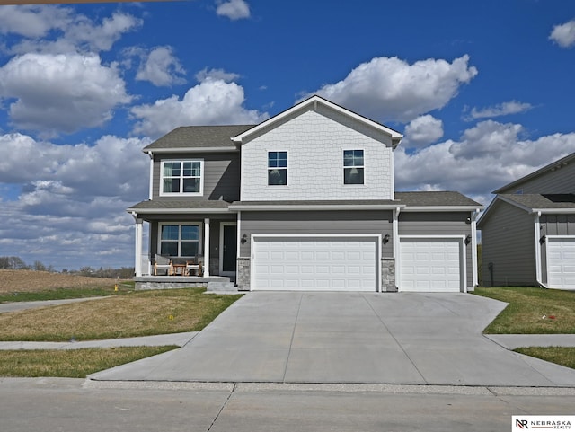 view of front of home featuring a front yard, driveway, an attached garage, and covered porch