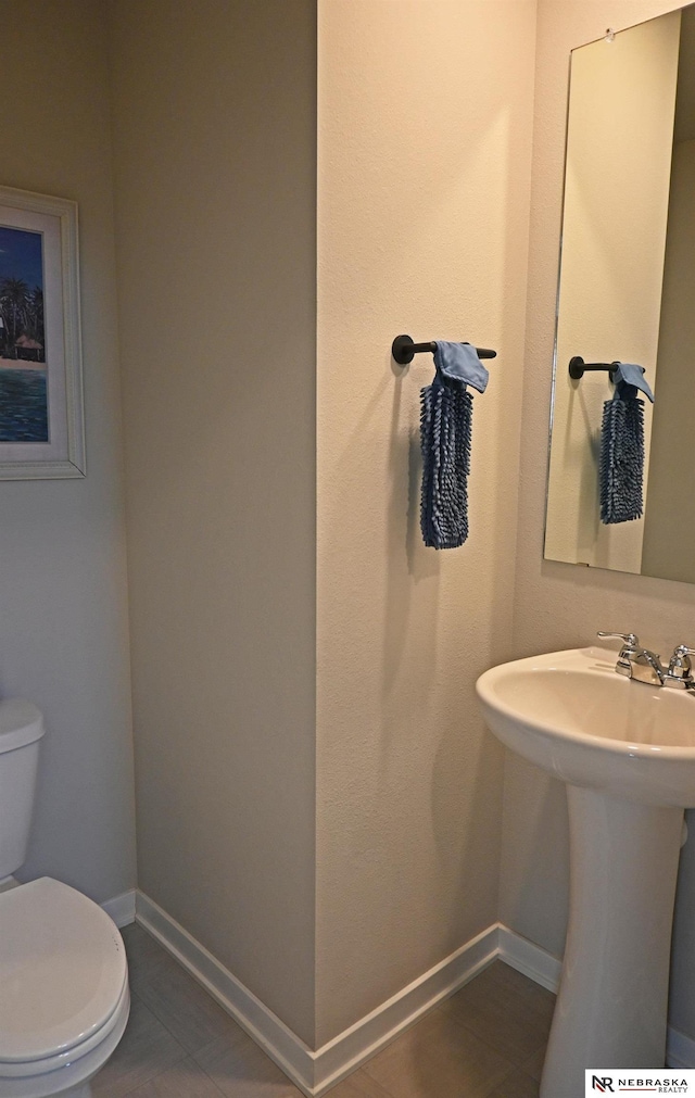 half bathroom featuring a sink, toilet, and baseboards