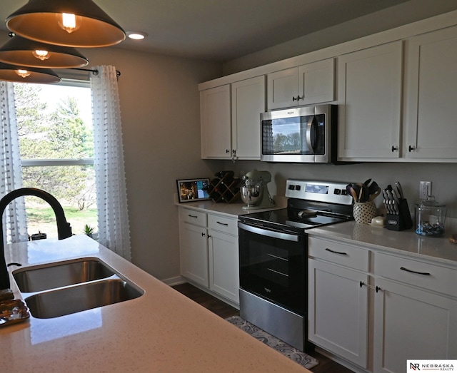 kitchen with light countertops, appliances with stainless steel finishes, a sink, and white cabinets
