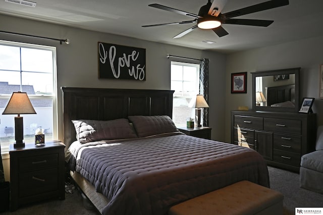 bedroom with dark carpet, a ceiling fan, and visible vents