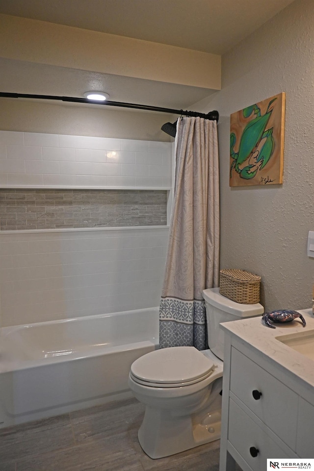 bathroom with toilet, shower / tub combo with curtain, vanity, and a textured wall