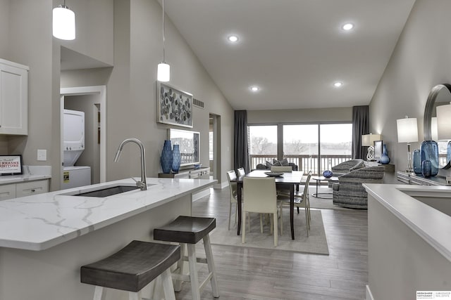 17045 Hawthorne Ave, Omaha, NE 68118 - kitchen featuring high vaulted ceiling, white cabinets, stacked washer / dryer, a sink, and open floor plan