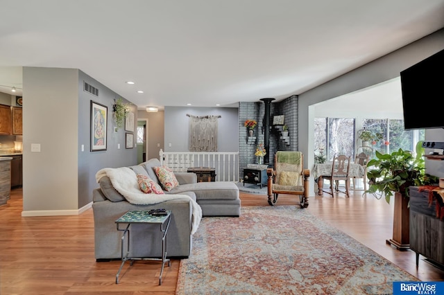 living area featuring recessed lighting, a wood stove, visible vents, and light wood-type flooring