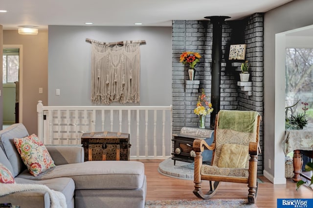living area with a wood stove, recessed lighting, wood finished floors, and a healthy amount of sunlight