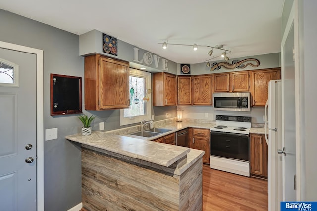 kitchen with electric range oven, a sink, a peninsula, brown cabinets, and stainless steel microwave
