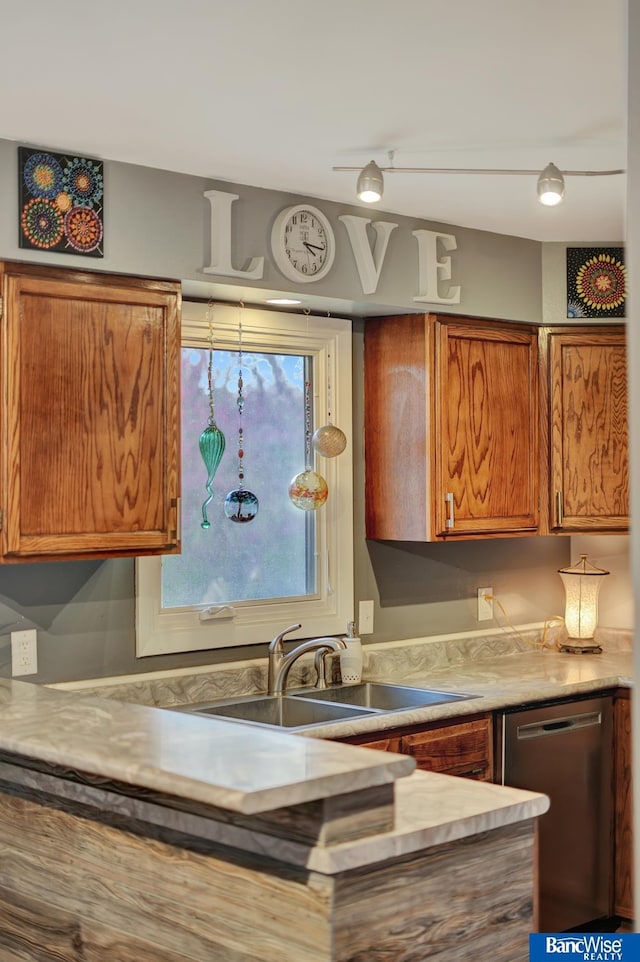 kitchen featuring brown cabinets, light countertops, dishwasher, and a sink