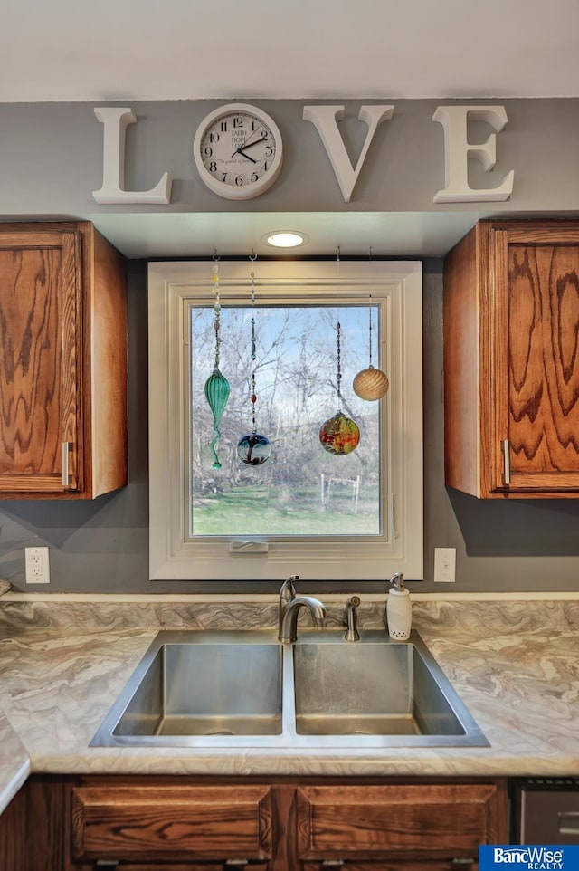 kitchen with brown cabinetry, light countertops, and a sink