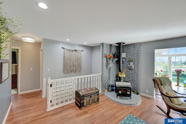 living area with wood finished floors, a wood stove, baseboards, and recessed lighting