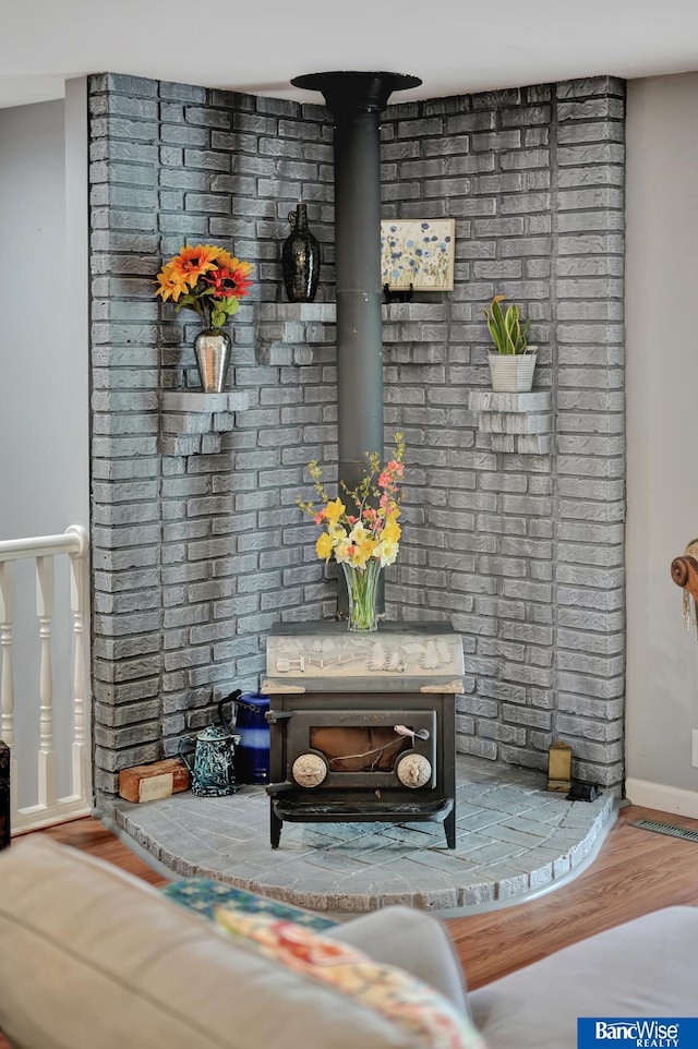 interior details featuring wood finished floors, a wood stove, and baseboards