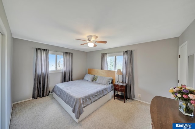 bedroom with a ceiling fan, light carpet, baseboards, and multiple windows