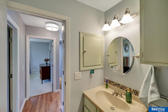 bathroom with backsplash, baseboards, vanity, and wood finished floors