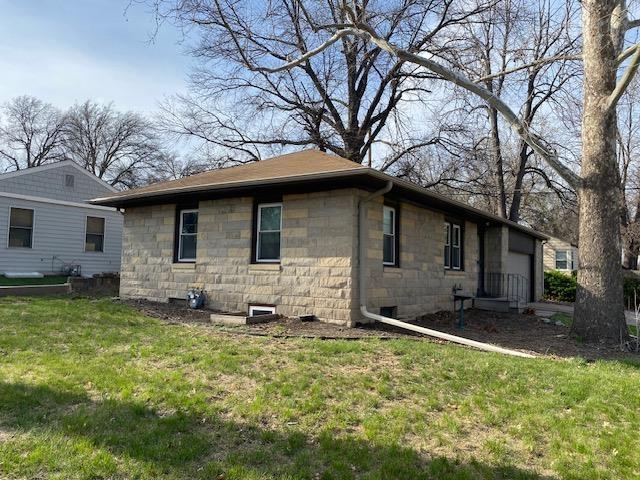 view of home's exterior with a garage, a yard, and stone siding
