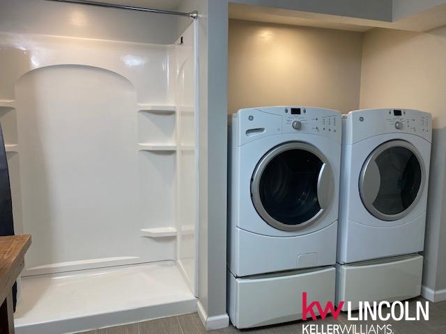 washroom featuring washer and dryer, laundry area, baseboards, and wood finished floors