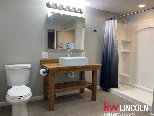 bathroom with toilet, baseboards, a sink, and curtained shower