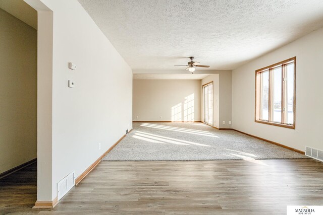 spare room with wood finished floors, baseboards, a ceiling fan, and visible vents