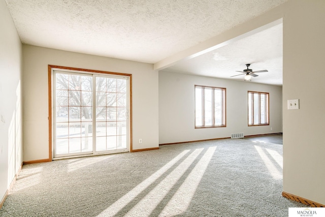 carpeted empty room with visible vents, baseboards, ceiling fan, and a textured ceiling