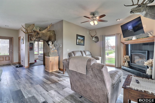 living area featuring ceiling fan, baseboards, wood finished floors, and a healthy amount of sunlight