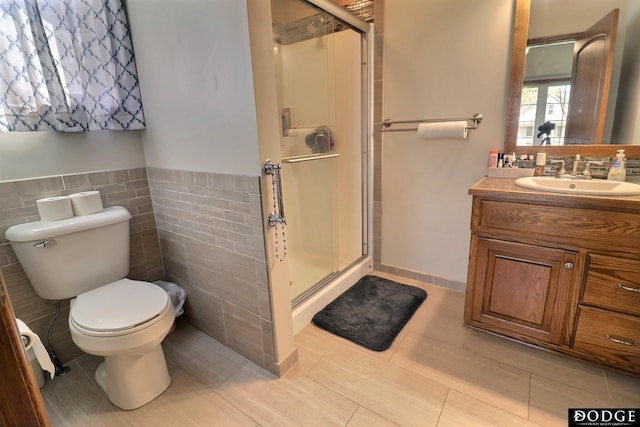 bathroom with toilet, tile walls, a shower stall, vanity, and a wainscoted wall