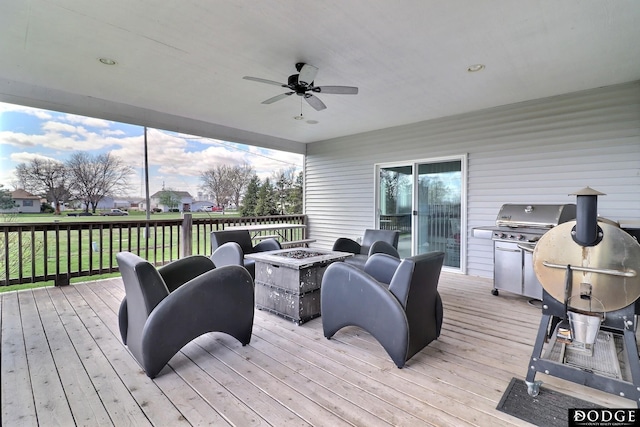 wooden deck featuring area for grilling, an outdoor fire pit, and a ceiling fan