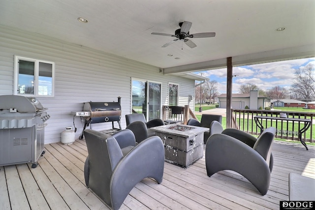 wooden terrace with an outdoor fire pit, a grill, and a ceiling fan