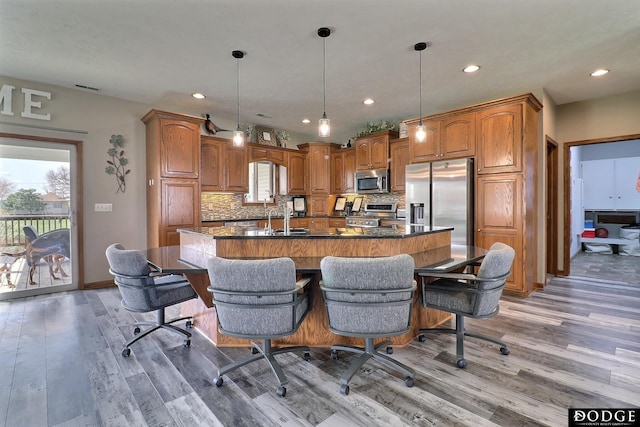 kitchen with tasteful backsplash, light wood-type flooring, dark countertops, and stainless steel appliances