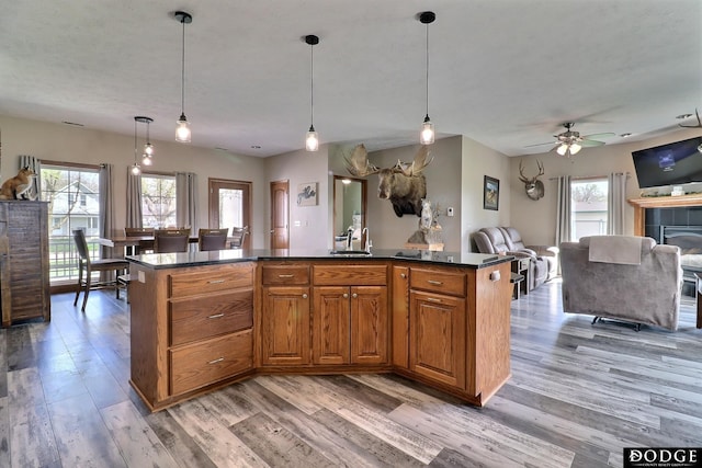 kitchen featuring brown cabinets, open floor plan, dark countertops, and light wood finished floors