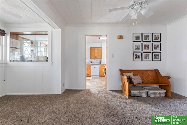 living area featuring light carpet, baseboards, ornamental molding, and a ceiling fan