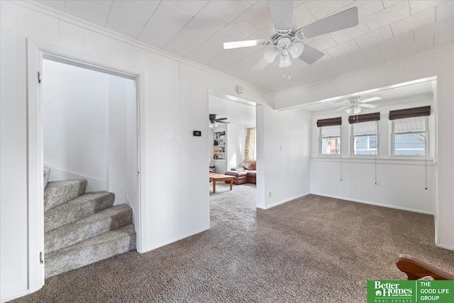 living room featuring baseboards, ceiling fan, crown molding, carpet floors, and stairway