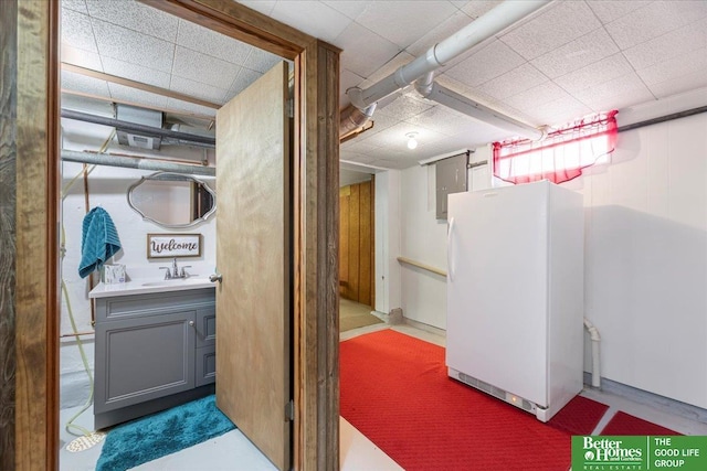basement featuring freestanding refrigerator, a sink, carpet flooring, and visible vents