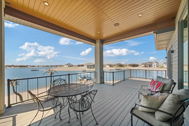 wooden terrace with outdoor dining space and a water view