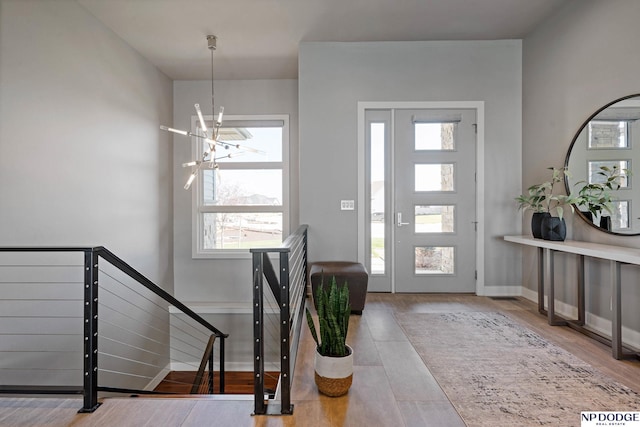 foyer featuring wood finished floors, a notable chandelier, and baseboards
