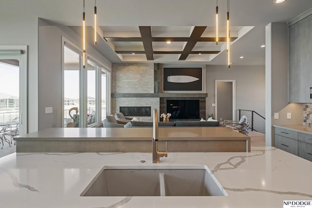 kitchen with a large fireplace, gray cabinets, beam ceiling, coffered ceiling, and a sink