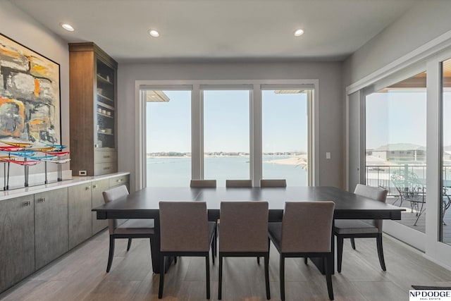 dining room featuring a water view, recessed lighting, light wood-style floors, and a healthy amount of sunlight