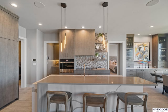 kitchen featuring tasteful backsplash, open shelves, oven, a breakfast bar, and recessed lighting