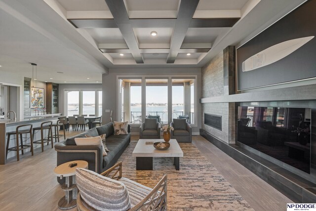 living area with a large fireplace, recessed lighting, beamed ceiling, coffered ceiling, and wood finished floors