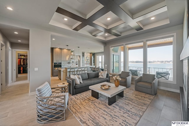 living room featuring coffered ceiling, baseboards, a water view, and a wealth of natural light