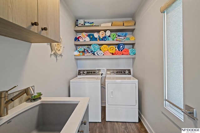 laundry room with baseboards, dark wood-type flooring, a sink, cabinet space, and washer and clothes dryer