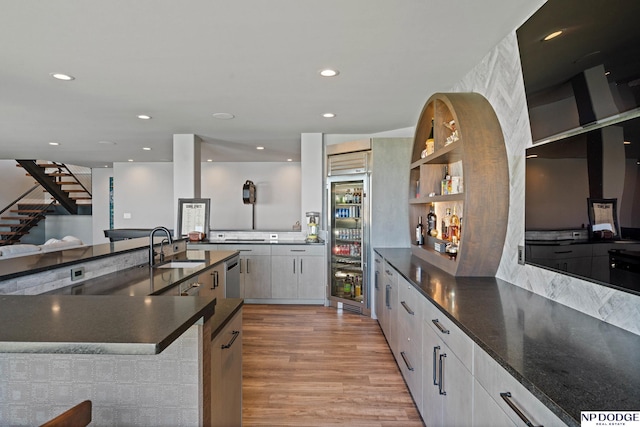 kitchen with open shelves, modern cabinets, stainless steel appliances, light wood finished floors, and a sink
