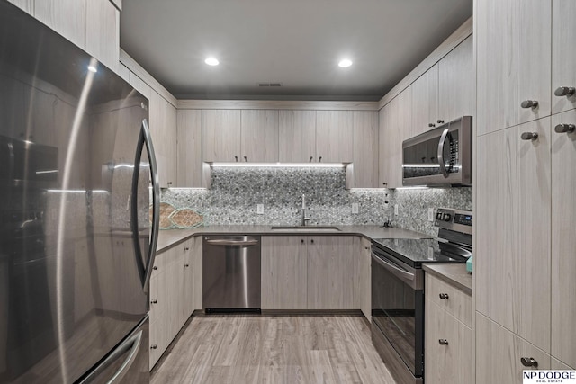 kitchen with a sink, backsplash, appliances with stainless steel finishes, and visible vents