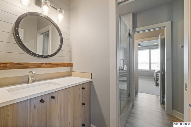 bathroom with tasteful backsplash, vanity, wood finished floors, a stall shower, and baseboards