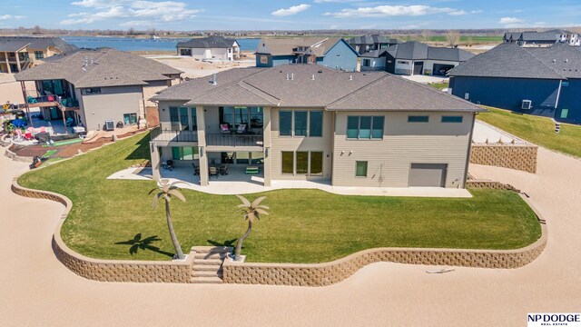 back of property featuring a balcony, a patio area, a residential view, and a lawn