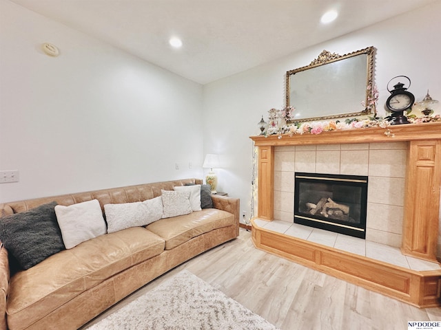 living room featuring recessed lighting, a tiled fireplace, and wood finished floors
