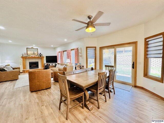 dining space with baseboards, recessed lighting, a fireplace, a ceiling fan, and light wood-style floors