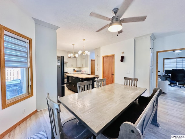 dining space with light wood-type flooring and ceiling fan with notable chandelier