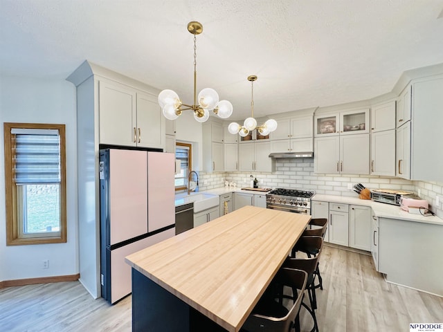 kitchen featuring a notable chandelier, a wealth of natural light, decorative backsplash, stainless steel appliances, and a sink