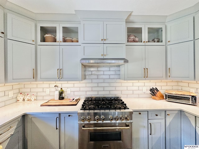kitchen featuring under cabinet range hood, stainless steel range, light countertops, and backsplash