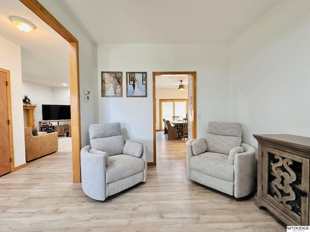 living area featuring light wood-style flooring and a ceiling fan