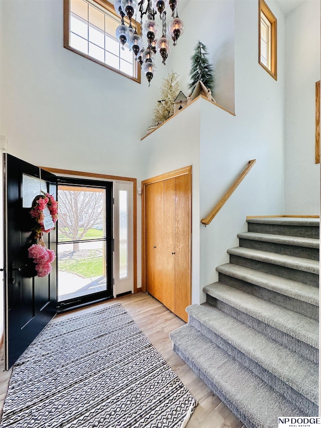 entryway featuring light wood-style floors, a high ceiling, an inviting chandelier, and stairs